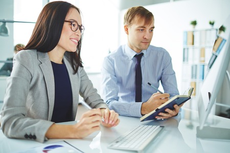 Two young colleagues planning work in front of computer monitorの写真素材