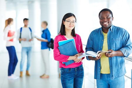 Cheerful students with books looking at cameraの写真素材