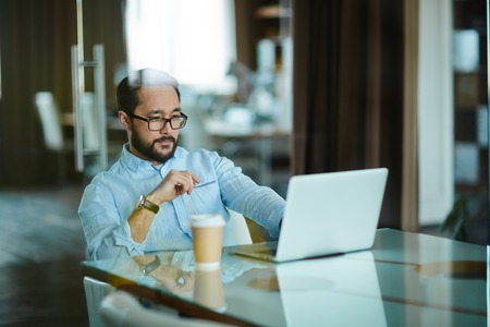 Asian businessman looking at laptop display at workplaceの写真素材
