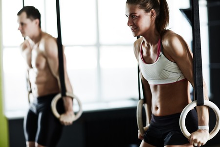 Two athletes training on sports rings