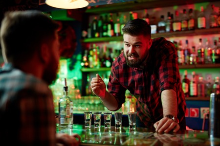 Bearded barman by counter talking to guyの写真素材
