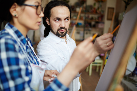 Teacher explaining main rules of painting to studentの写真素材