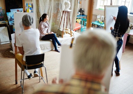 Group of students drawing young girl posing in workshopの写真素材