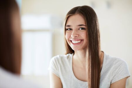 Young beautiful woman with perfect teeth smiling at mirrorの写真素材
