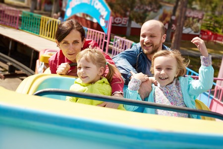 Family of four having fun in amusement parkの写真素材