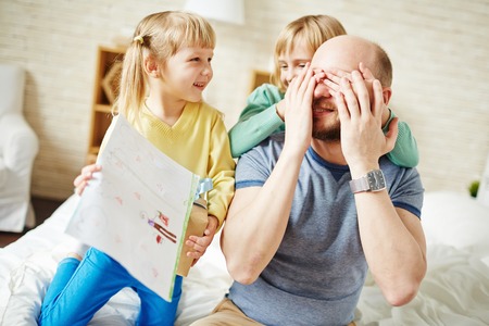 Little girls with packed gift congratulating their dadの写真素材