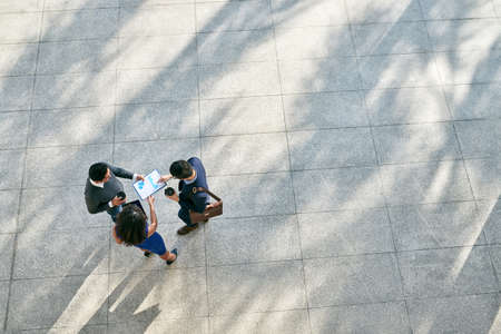 Coworkers discussing business chart outdoors, view from aboveの写真素材