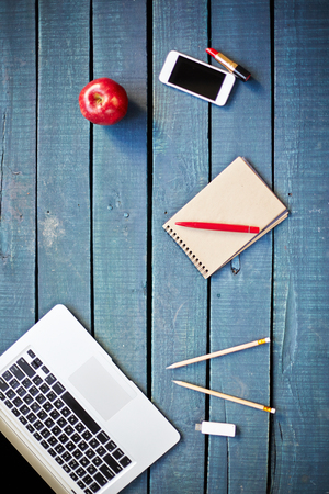 Laptop, notepad, smartphone, apple and lipstick on wooden tableの写真素材