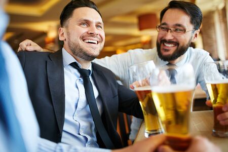 Happy men in formalwear drinking beerの写真素材