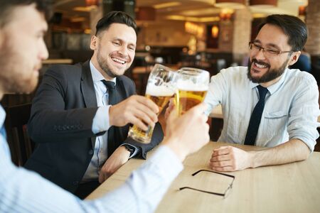 Contemporary employees toasting with beer in barの写真素材