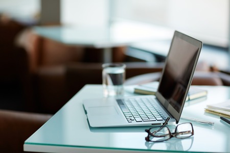 Laptop, pen and eyeglasses on deskの写真素材
