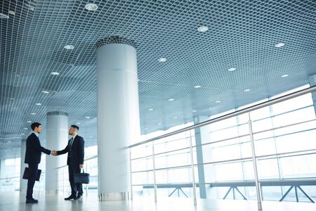 One of floors of modern business center with two partners handshakingの写真素材