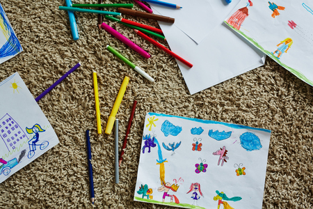 Drawn pictures and colorful crayons on the floor