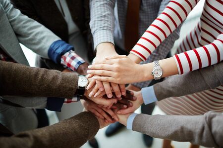 Hands of business partners making pile