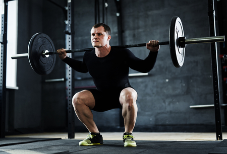 Strong young man with weight training in gymの写真素材