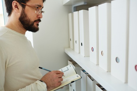 Businessman making notes in officeの写真素材