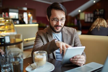 Businessman with touchpad networking in cafeの写真素材