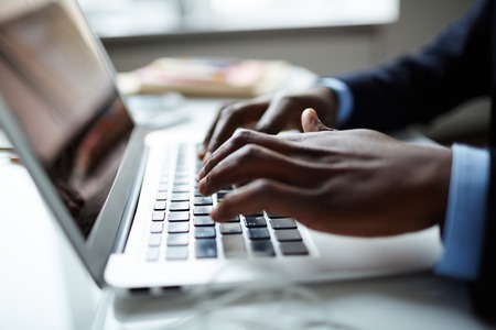 Fingers of businessman over laptop keypadの写真素材