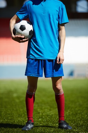 Young footballer with soccer ball standing on the fieldの写真素材