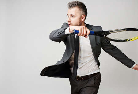 Businessman with tennis racket ready to oppose financial difficulties or economic crisis, he is sure...