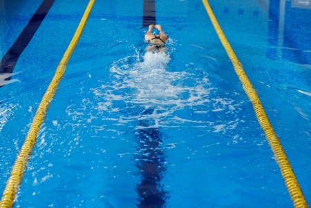 Young woman swimming in blue water of indoor race poolの写真素材