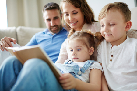 Family of four reading book at leisureの写真素材