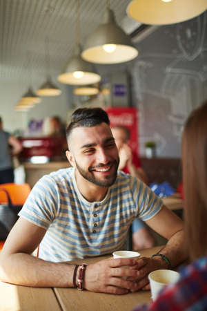 Happy guy talking to girlfriend by coffeeの写真素材