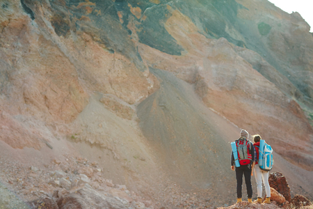 Two hikers with backpacks standing by mountainの写真素材