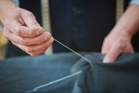 Hands of experienced tailor sewing at workの写真素材