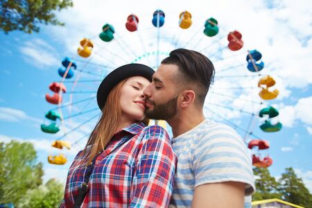 Amorous young couple kissing on background of amusementの写真素材