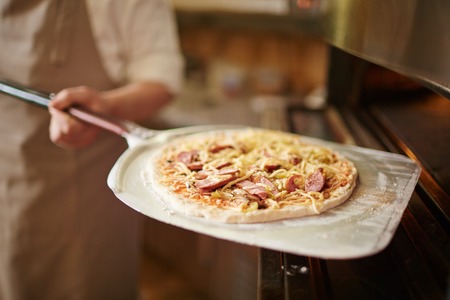 Chef holding raw pizza ready for bakeの写真素材