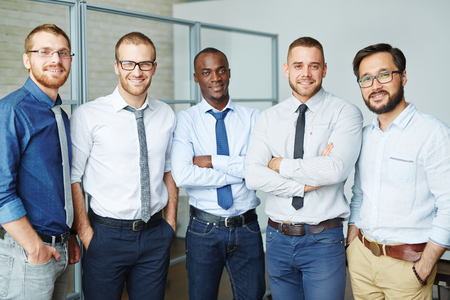 Multi-ethnic employees in formalwear looking at camera in office