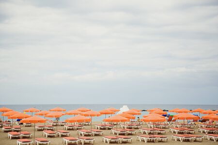 Beach for sunbathers with chaise-longues and umbrellasの写真素材