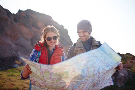 Happy tourists looking at map during trip