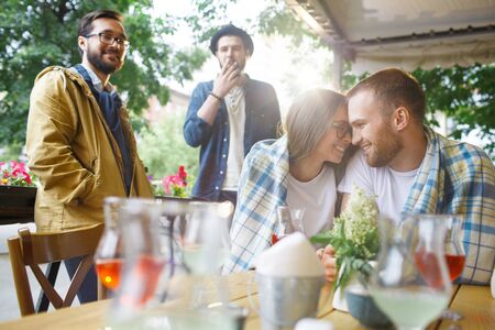 Happy couple enjoying time in cafe with friends near by