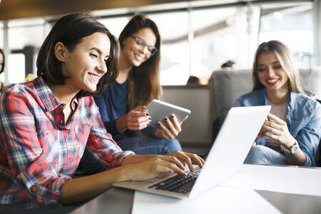 Cute students working with modern gadgetsの写真素材