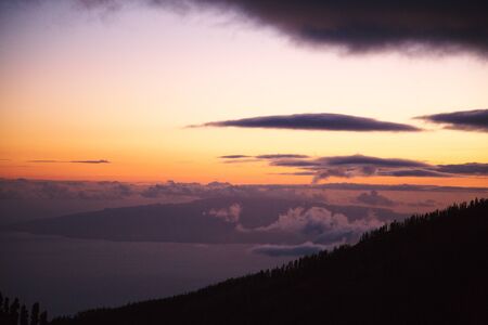 Cloudscape over hill or mountain covered with treesの写真素材