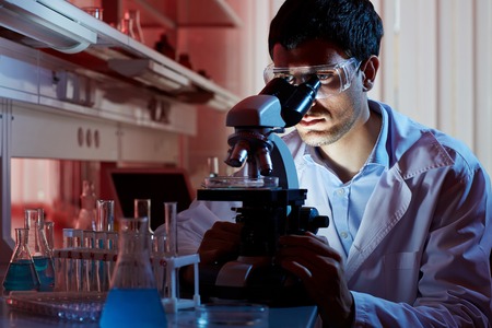Young clinician in protective eyeglasses studying new vaccine