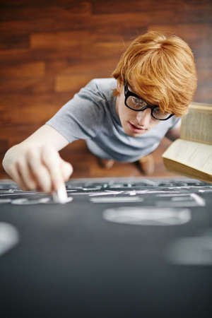Student with book writing on blackboard with chalkの写真素材