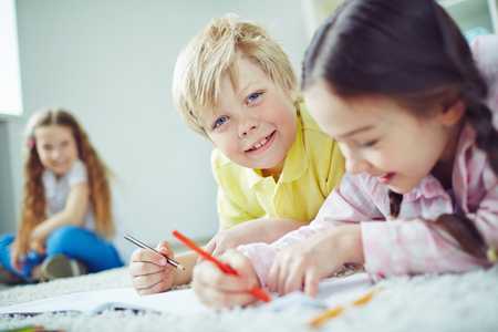 Cute boy with pencil and his friend drawing togetherの写真素材