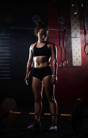 Young woman looking at weight on the floor of gymの写真素材