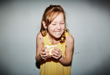 Cute girl eating tasty cake and laughingの写真素材