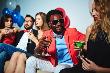 Intercultural couple with drinks talking at party
