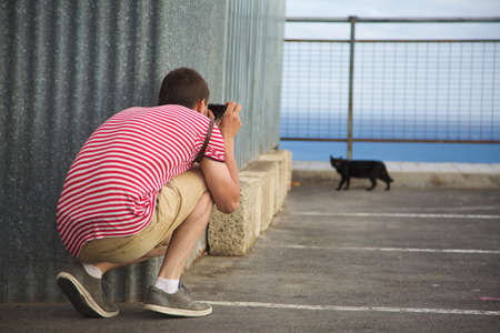 Traveling photographe taking photo of black catの写真素材