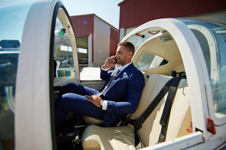 Elegant businessman calling in cabin of airplane