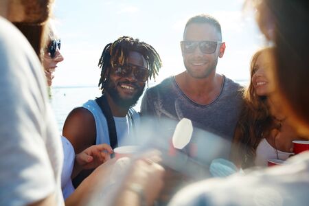 Happy young men in sunglasses spending time outdoors with their friendsの写真素材