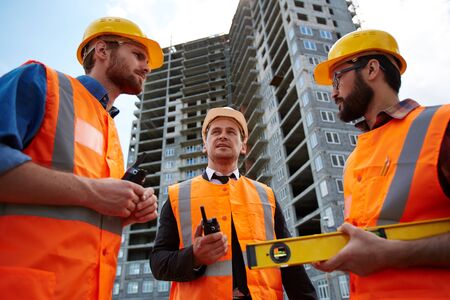 Modern architects discussing unfinished building behind them