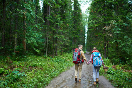 Couple of tourists walking down forest path