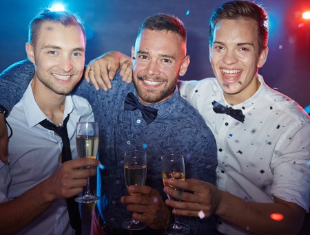 Three elegant guys with champagne looking at camera at partyの写真素材