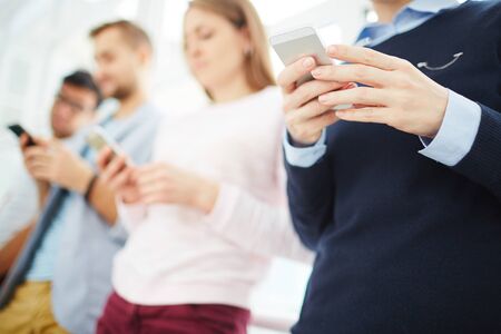 Close-up of people standing with smartphones indoors